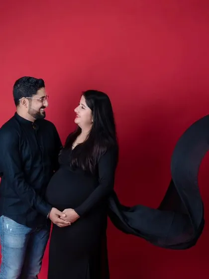 Maternity sessions are a beautiful way to celebrate the anticipation and glow of pregnancy. In my studio, we can create dramatic and elegant portraits using props like this flowing black gown against a bold red backdrop for a timeless look.