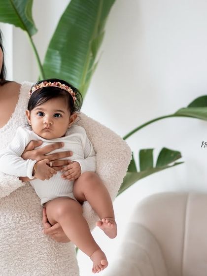 A mother holding her baby girl by the window, using the beautiful natural light of the studio.