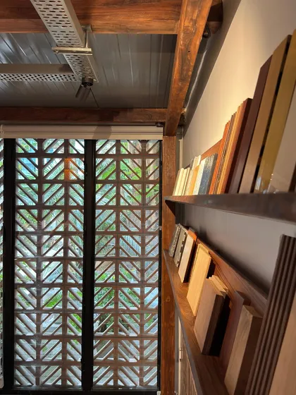 A side view of the material library shelves in our studio extension, lit by LED strips. The terracotta jali screen is visible in the background, connecting the interior to the natural light outside.