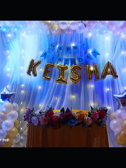 A close-up of the birthday stage, showing the 'Happy Birthday Keisha' foil balloons and the beautiful lighting effect.