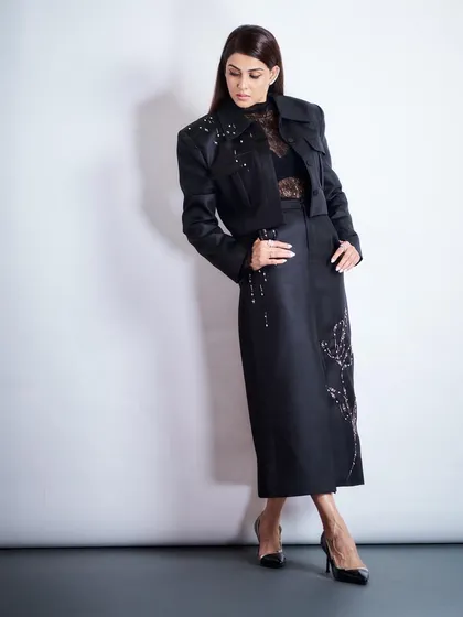 Genelia D'Souza in a sophisticated all-black ensemble. The look features a structured, embellished jacket over a lace top and matching skirt, creating a modern and powerful silhouette.