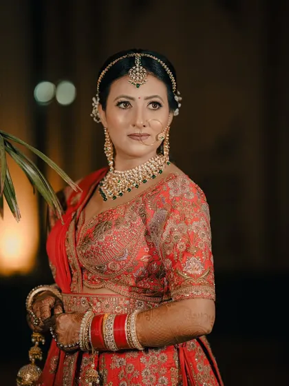 An elegant outdoor portrait of a bride. We focus on her striking pose and the intricate details of her jewelry and embroidered blouse.
