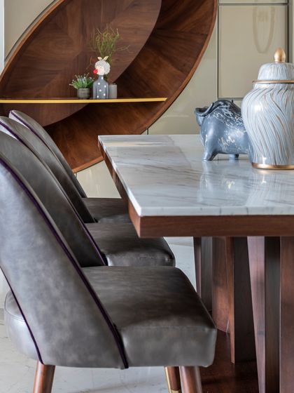 A detail of the dining table at the Filigree House. The elegant grey leather chairs with purple piping and the marble tabletop showcase my commitment to refined details and high-quality materials.