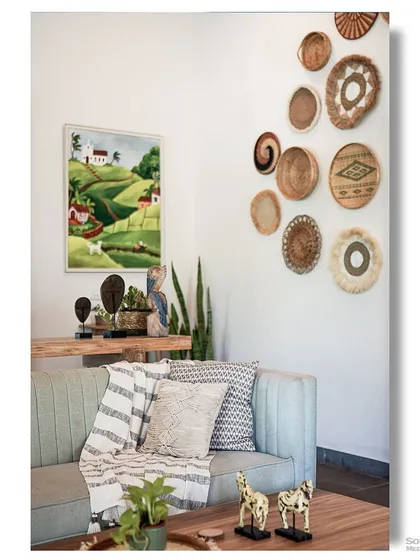 A cozy corner in a Goan homestay, featuring a comfortable sofa, a gallery wall of woven baskets, and other eclectic decor. The style is bohemian, relaxed, and full of personality.