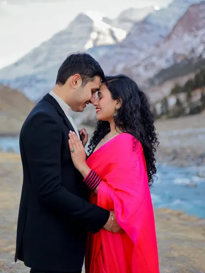 An intimate close-up of a couple against the backdrop of a river and snow-dusted mountains in Himachal.