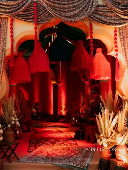 A grand entrance designed with rich textures and dramatic lighting. The red drapes and pampas grass arrangements create a luxurious and theatrical welcome for guests.