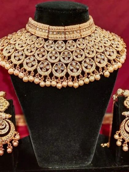 A classic gold-plated Polki choker set with matching chandbali earrings. The pearl drops add a touch of elegance to this timeless design.