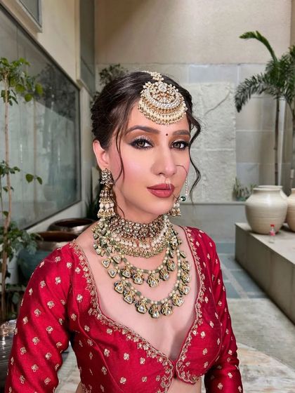 A close-up of the bride's face, showing the detailed maang tikka and the soft, elegant makeup.