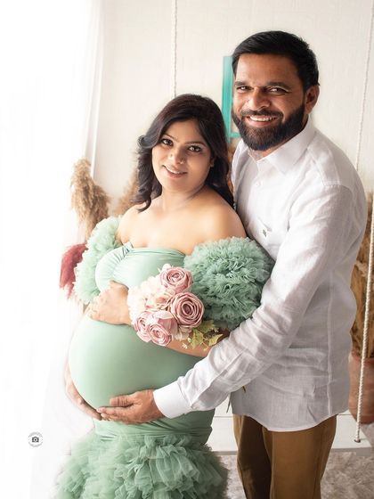 A joyful couple's portrait. They are both smiling at the camera, capturing a happy memory from their pregnancy journey.