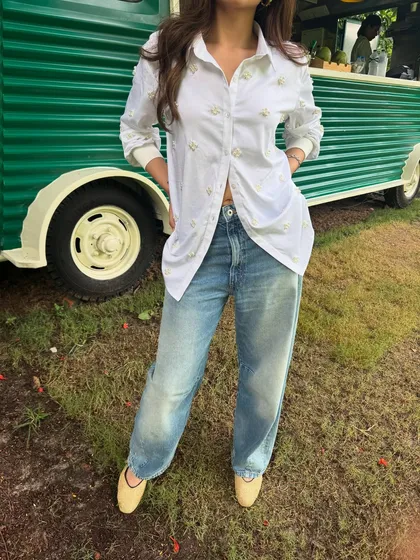 A close-up of the embroidered details on this white shirt, which adds a unique touch to the classic shirt-and-jeans pairing.