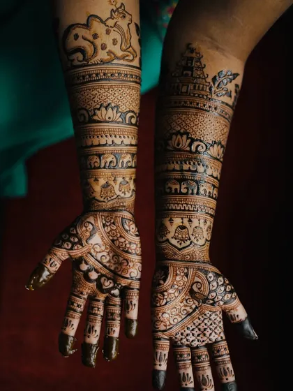 This South Indian bridal design is rich with personal and cultural symbols, including temple gopurams, elephants, and a sacred cow with its calf (Nandi).