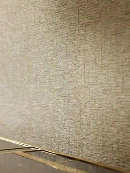 A close-up of the “Lioube” wallcovering. The intricate weave and shimmering lurex threads are visible, showcasing the high-quality texture that defines this luxurious design.