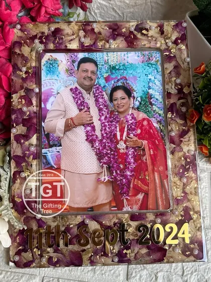 A direct frontal view of the anniversary frame, showing the preserved purple and white flowers creating a beautiful border.