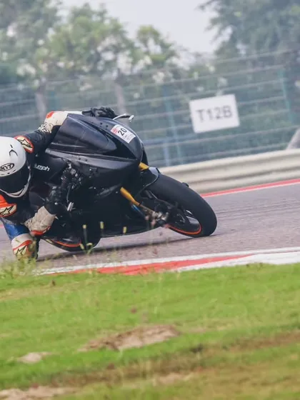 A rider with a distinctive helmet pushes their bike to a sharp lean angle, demonstrating the skills and confidence built at our academy.