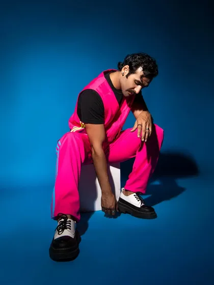 The combination of the bright pink athleisure wear and the bold blue background creates a vibrant, color-blocked fashion statement.