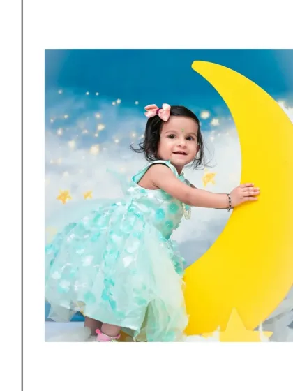 This little star is all smiles as she poses next to a big yellow moon. Her mint green dress and the starry sky backdrop create a sweet and whimsical portrait.