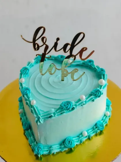 A heart-shaped "Bride to Be" cake in a beautiful teal color, perfect for a bridal shower.
