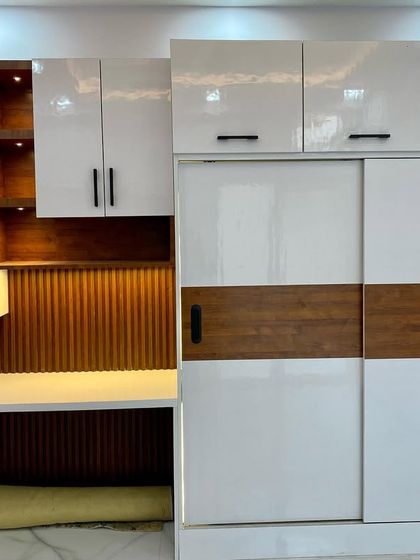 A beautiful and functional unit featuring a sliding wardrobe next to a study table with open-lit shelves and overhead cabinets.