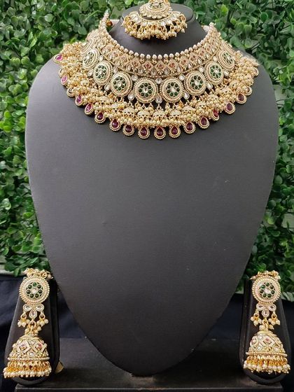 A beautiful kundan choker set with green and red accents, paired with matching jhumkas. This is a very popular style for wedding ceremonies.