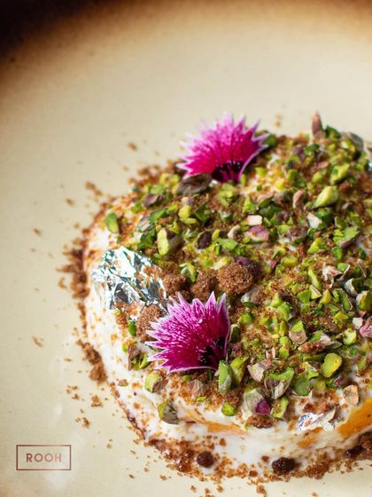 A close-up of the Mango Malai, adorned with edible silver. It's a celebration of seasonal fruit and traditional Indian dairy, a truly soulful dessert.