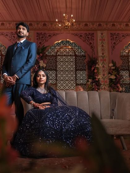 A wide shot of the couple on their grand reception stage. Dr. Akshara's look is designed to be impactful and stunning from a distance.