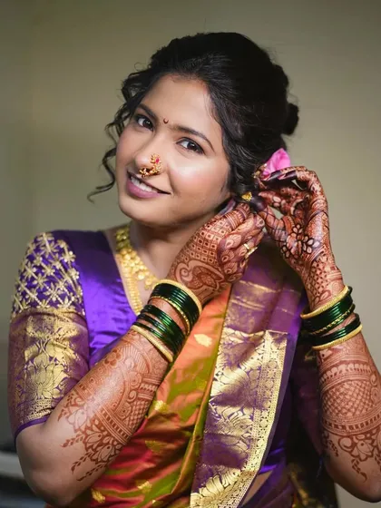 A close-up of a bride getting ready. This shot captures the intricate details of her henna and the soft, romantic curls of her hairstyle.