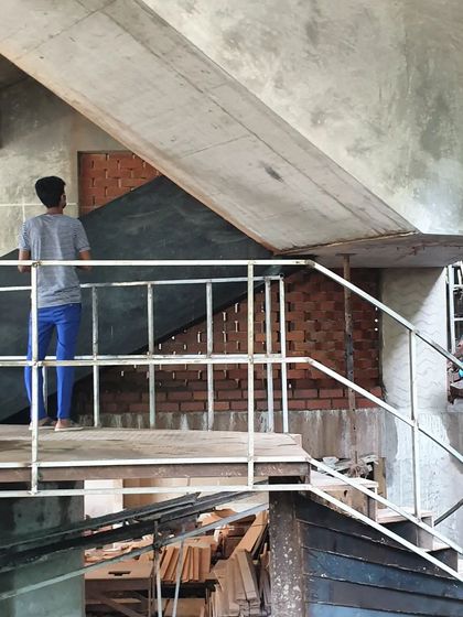A worker navigates the complex formwork of the Brick House staircase. This image captures the immense skill and labor involved in translating our geometric designs into physical form.