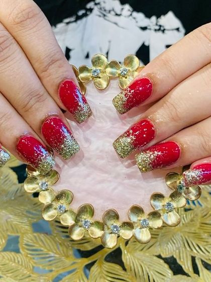A festive and bold look with bright red nails and a chunky gold glitter accent on the tips.