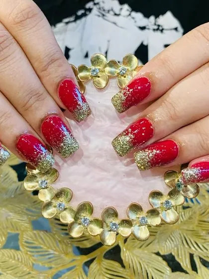 A festive and bold look with bright red nails and a heavy gold glitter gradient on the tips.