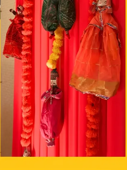 A close-up of the traditional decor elements, showing the colorful Rajasthani puppets and marigold strings against a vibrant red drape.
