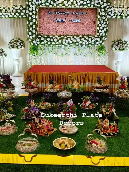 A full platter arrangement I created for an ear piercing ceremony in Coimbatore. The display includes a variety of decorated plates featuring dolls, fresh fruits, and flowers, all set up beautifully at the Arunai Arangam Mandapam.