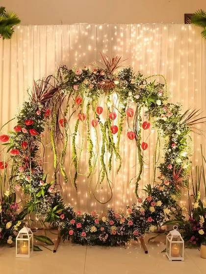 A unique and artistic floral ring backdrop. The design incorporates hanging tulips and wild grasses, creating a modern and organic photo point for an engagement or reception.
