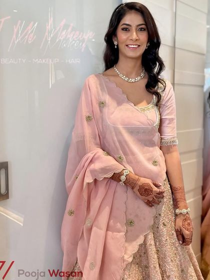 This client is glowing with a soft, romantic makeup look for her engagement. The subtle pink tones on the eyes and lips harmonize beautifully with her pastel lehenga and simple diamond jewelry.