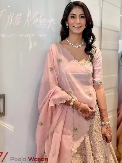Elegance in pastel pink. This soft and sophisticated look is perfect for a day wedding or a reception, featuring gentle waves and natural-looking makeup that enhances her features.