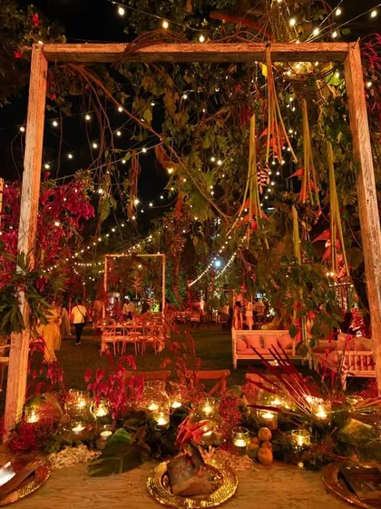 To celebrate the traditional festival of Lohri, I created an enchanting outdoor setting under a canopy of stars and string lights. The decor features unique table structures adorned with hanging vegetables and florals, all bathed in a warm red glow to evoke a feeling of festive passion.