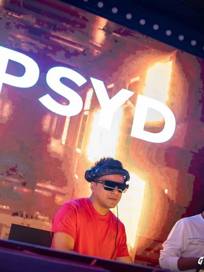 A close-up portrait from a gig in Kolkata, with my name on the big screen behind me.