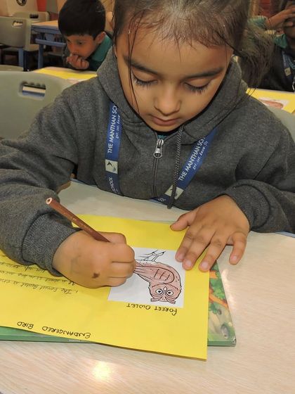 A student carefully colors a picture of a forest owlet, learning about endangered species. Our curriculum integrates important lessons on conservation and kindness to animals.