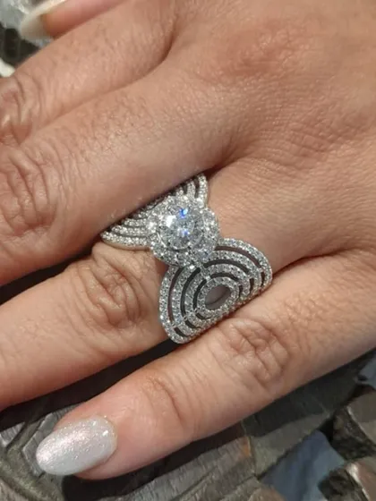 The beauty of a custom diamond ring on the hand. This piece, with its sparkling 1-carat solitaire and intricate pavé band, is crafted in 18kt gold and designed to be a cherished symbol for years to come.
