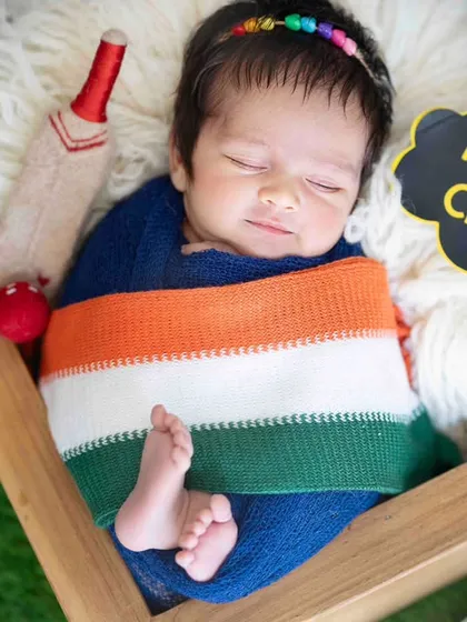A future cricket star. This newborn is wrapped in the Indian tricolor for a women's cricket theme, celebrating our nation's sporting spirit.
