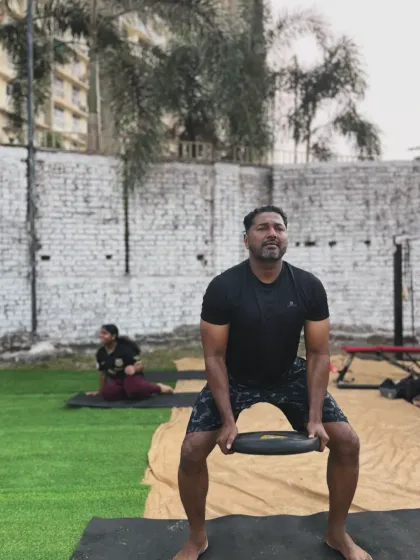 An athlete using weights to intensify his squats during an outdoor session. We use a variety of tools to maximize results.