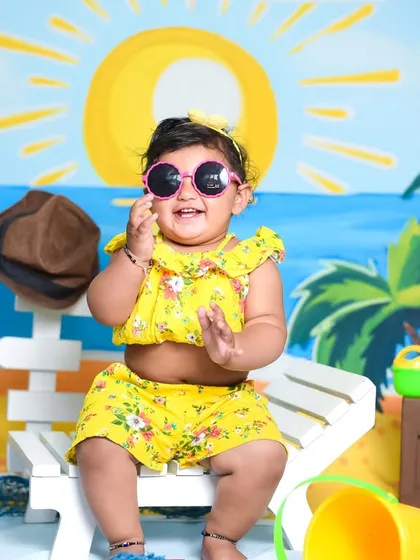 A sunny beach theme for a happy baby girl. Even indoors, we can create a fun summer vibe with a painted backdrop, beach chair, and playful props.