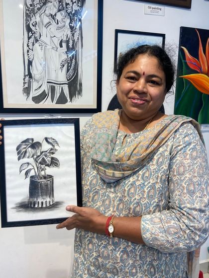 A student proudly holds her finished charcoal drawing. Our workshops and courses are designed to help you create art you'll love.