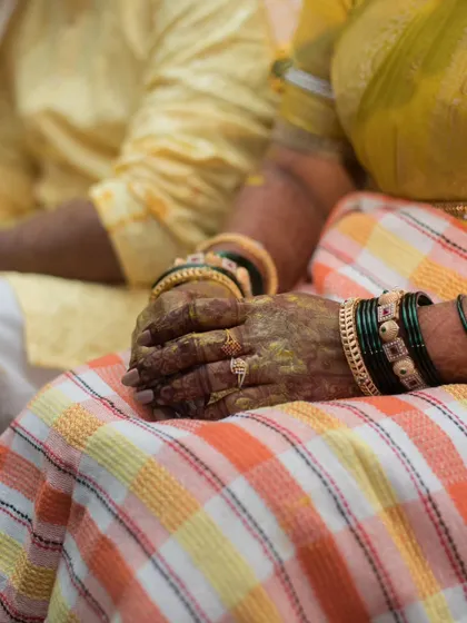 A detail shot of the bride's hands, covered in turmeric paste, resting during her Haldi ceremony. This captures the essence of the ritual.