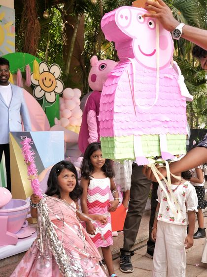 Kids having fun with a Peppa Pig piñata, a classic party game that's always a hit.