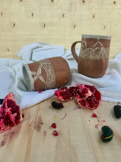 The Déesse mugs styled with fresh pomegranates. The rich texture of the clay and the sharp detail of the carving create a beautiful contrast with natural elements.