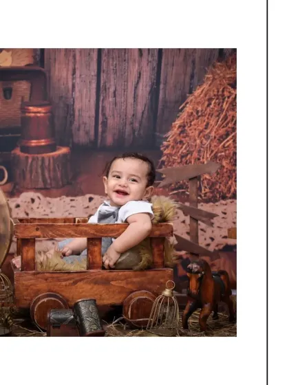 A beautiful, happy portrait of the baby boy in the vintage cart setup. His bright smile and the warm, rustic tones of the photo create a memory that will be cherished for years.