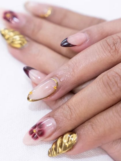 Artistry in every detail. This manicure features a beautiful combination of 3D gold textures, rich burgundy florals, and a sharp, modern nail shape.