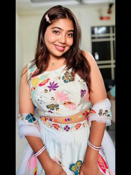 This smiling portrait captures the cheerful and youthful vibe of the hand-painted pastel lehenga. It's a perfect rental for a fun and festive occasion.