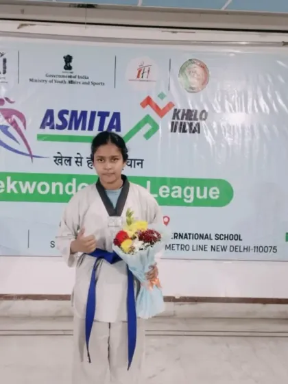 A blue belt student holding a bouquet after her performance at the Asmita City League. We celebrate the efforts of all our students.