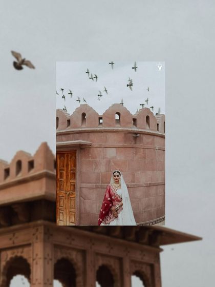 An artistic composition with the bride framed by the architecture of a Jodhpur palace, with birds flying overhead. This shot feels grand, poetic, and full of stories.